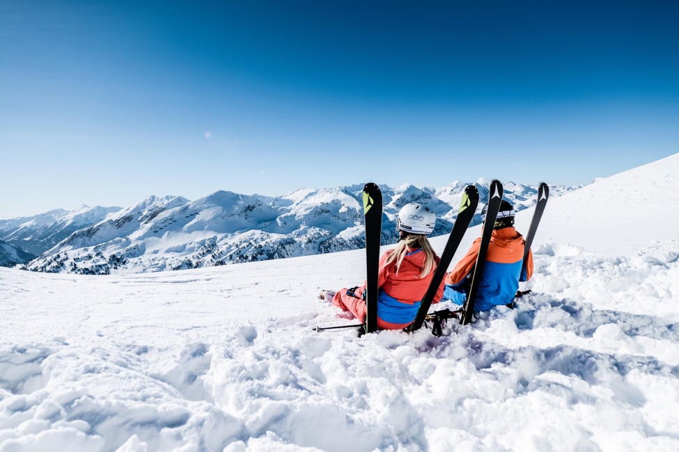 Zwei Skifahrer genießen die Aussicht in einem schneebedeckten Gebirge unter blauem Himmel ©TVB_Obertauern