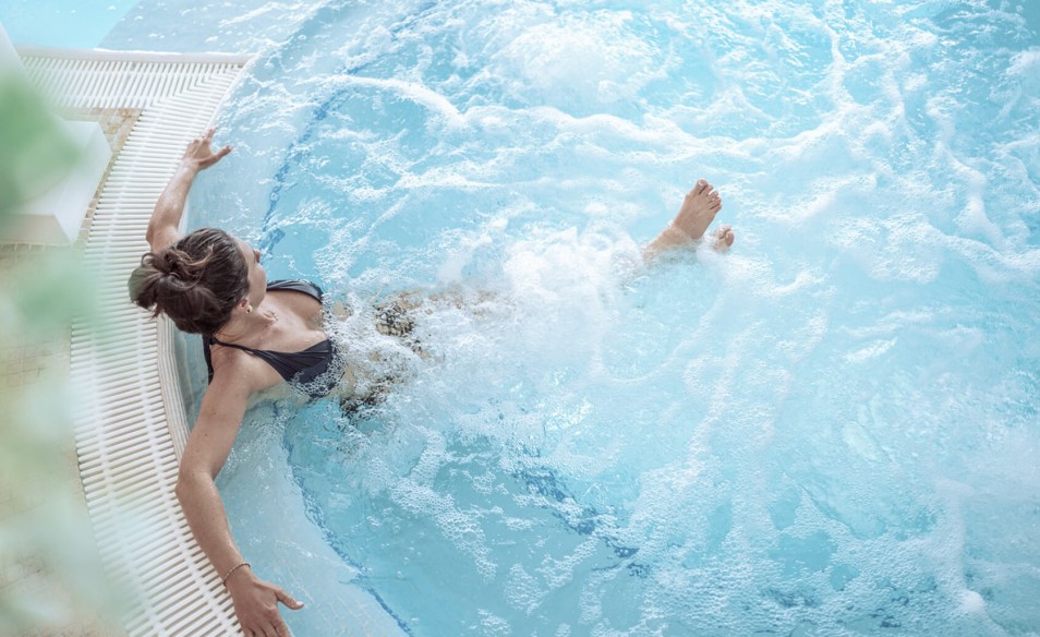 Woman relaxes in the warm water of the hotel pool.